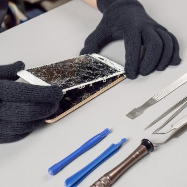 Technician or engineer opening broken smartphone for repair or replace new part on desk